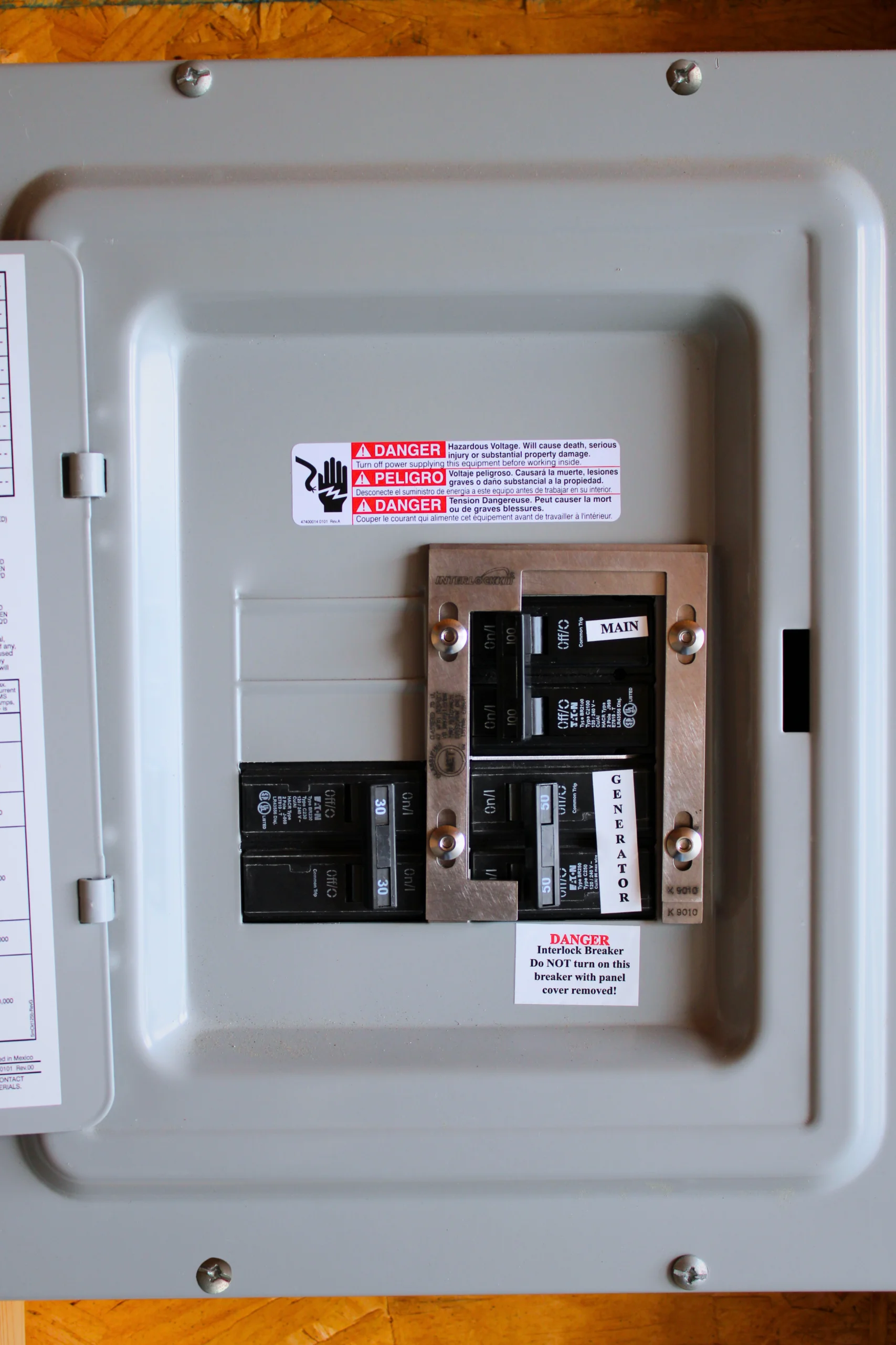 Generator Interlock Kit Installed on Electrical Panel Electrical panel with a generator interlock kit installed, showing main and generator breakers with safety labels