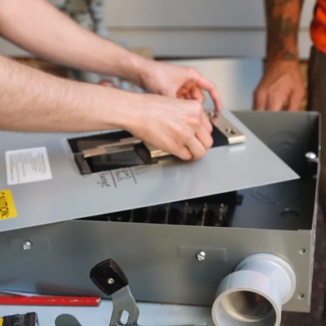 Contractor installing a generator interlock kit on a residential electrical panel
